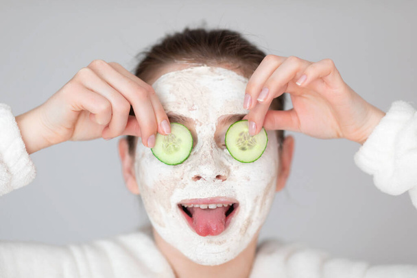 Aantrekkelijk meisje met plakjes komkommer op haar ogen. Beauty & Skin care concept - Foto, afbeelding