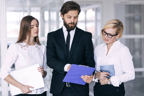 Diverse staff members confident smile business team holding document notepad and tablet device standing in modern office hallway looking at camera, boss and subordinates ready for negotiations concept - Foto, Imagen