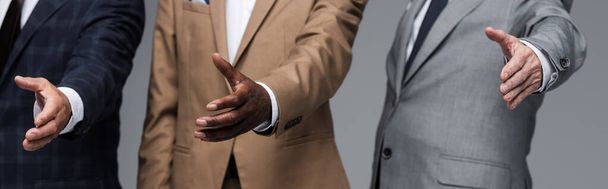 visão parcial de empresários seniores de pé com as mãos estendidas isoladas em cinza, banner - Foto, Imagem