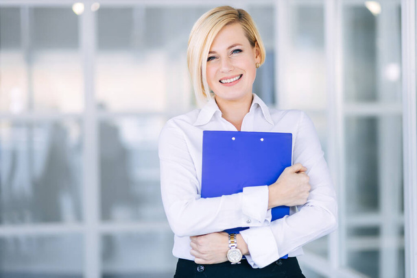 Beautiful blonde business woman in classic clothes with a folder of documents in her hands. - Foto, Imagem