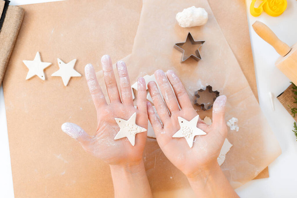 Female hands holds two cookies in the form of Christmas stars. Flat lay. Festive home-cooked meals. - Zdjęcie, obraz