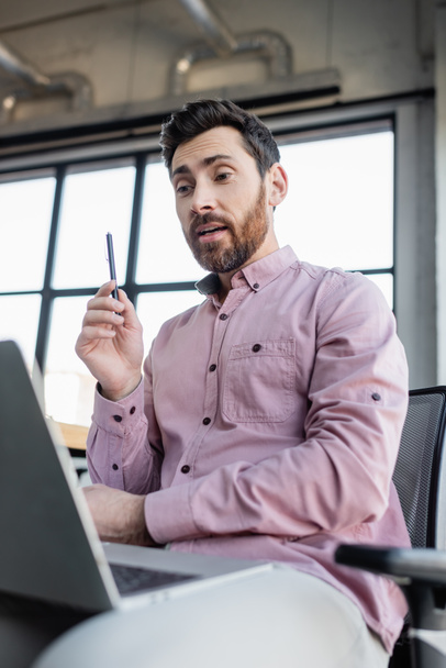 Üzletember ingben tartja toll közben videohívás laptop az irodában  - Fotó, kép
