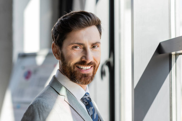 Portrait of businessman in suit smiling at camera in office  - Fotoğraf, Görsel