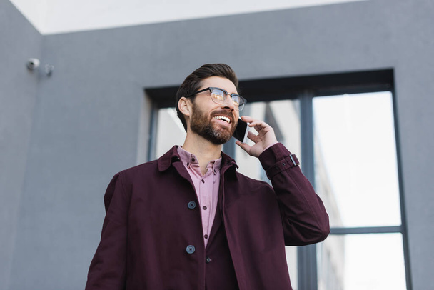 Homme d'affaires en trench coat parlant sur téléphone portable dans la rue urbaine  - Photo, image