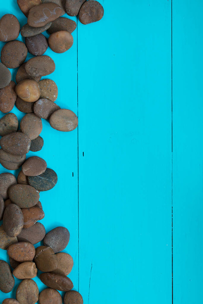 Kieselsteine auf der Seite über einem strukturierten blauen Hintergrund - Draufsicht mit Kopierraum - Foto, Bild