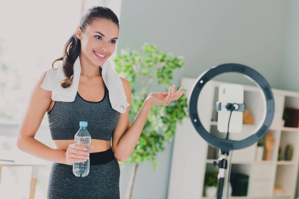 Photo of charming cute lady wear sport outfit smiling drinking water recording video indoors home house - Foto, Bild