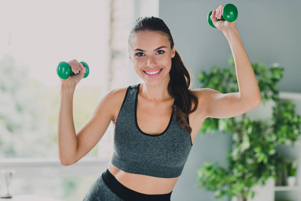 Photo of pretty charming lady wear sport outfit smiling holding dumbbells indoors home house - Photo, Image