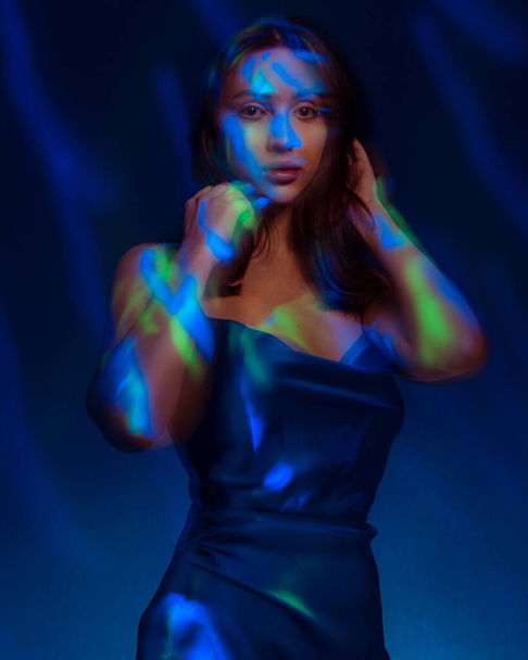 Portret in de stijl van licht schilderen. Brunette vrouw in blu jurk lange blootstelling foto, abstract portret licht en freezelight achtergrond - Foto, afbeelding