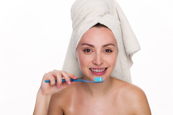 Cute and excited beautiful woman holds toothbrush and wearing towel on her head. Female has cleen skin shows white teeth, poses with naked body isolated over white background - Photo, Image