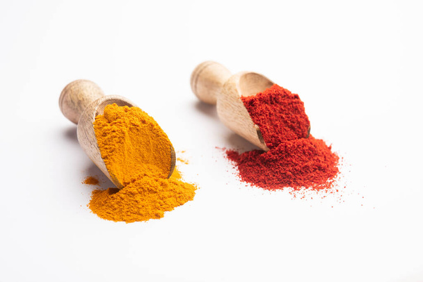 Turmeric and red chilli powder in a wooden measuring scoop or spoon on a white background - Fotografie, Obrázek