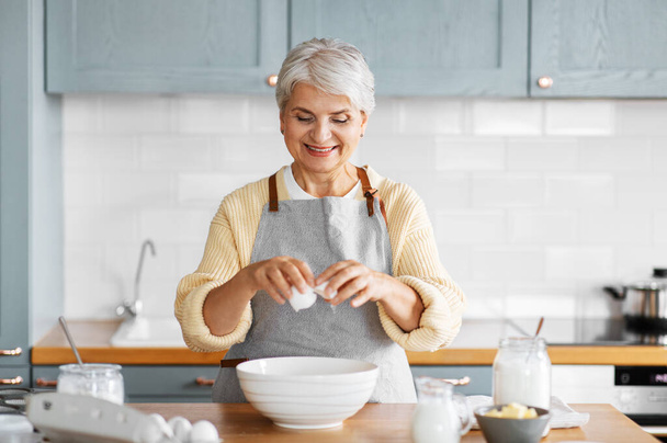 happy woman cooking food on kitchen at home - Valokuva, kuva