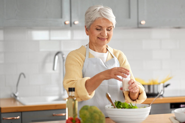happy woman cooking salad on kitchen at home - Φωτογραφία, εικόνα