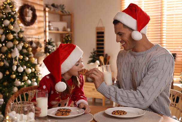 Happy father and his daughter eating delicious Christmas cookies at home - Foto, Bild