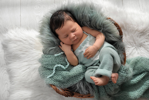 Cute newborn baby sleeping in wicker basket, top view - Фото, изображение