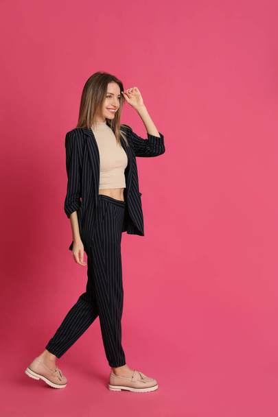 Full length portrait of beautiful young woman in fashionable suit on pink background. Business attire - Fotoğraf, Görsel