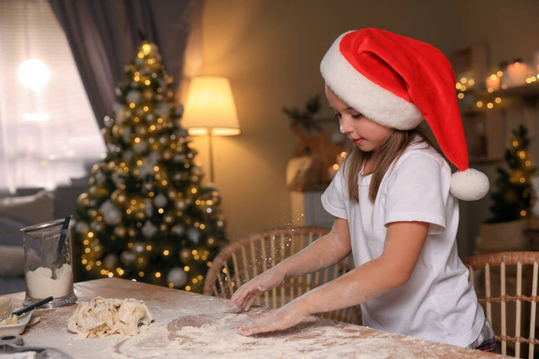 Χαριτωμένο κοριτσάκι έχει τη διασκέδαση, ενώ κάνει ζύμη για τα Χριστούγεννα μπισκότα στην κουζίνα - Φωτογραφία, εικόνα
