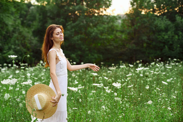 Woman in white dress and hat in a field with flowers lifestyle - Фото, изображение
