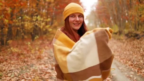 幸せな若い女性の肖像画は、公園で秋に秋の帽子とスカーフを身に着けている、居心地の良い暖かい服 - 映像、動画
