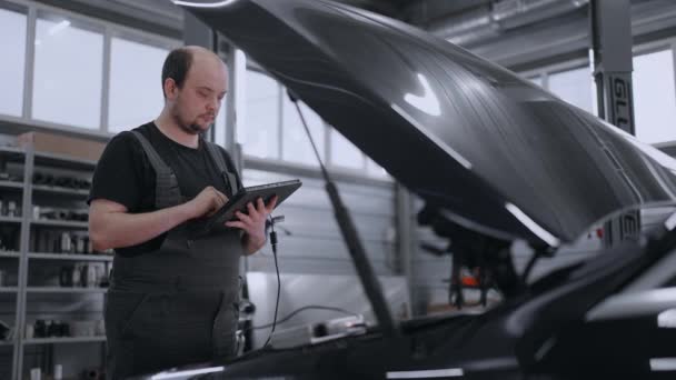 Diagnose des Autos auf der Motorhaube im Autoservice mit einem Tablet. Mechanik - Filmmaterial, Video