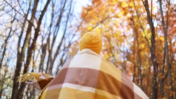 Mature woman in bright stylish clothes with a long yellow scarf whirls around enjoying autumn golden alley outside, having fan during fall season - Footage, Video