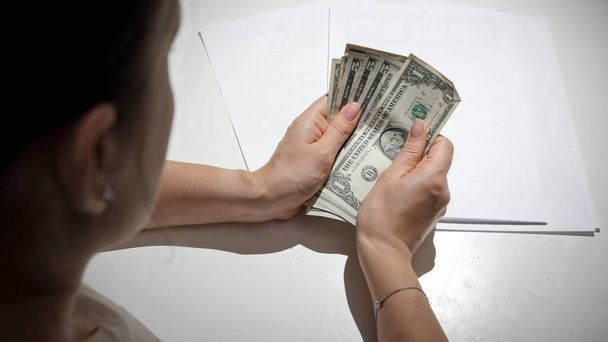 CLoseup de mujer joven que tiene dificultades financieras contando su dinero detrás de la mesa de la cocina - Foto, imagen
