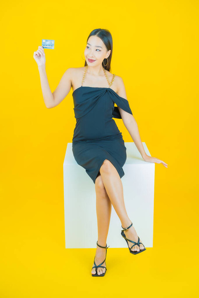 Retrato hermosa joven asiática mujer sonrisa con tarjeta de crédito en color de fondo - Foto, imagen