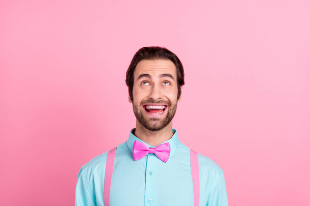 Photo of cute excited young man wear turquoise outfit smiling looking up empty space isolated pink color background - Fotografie, Obrázek