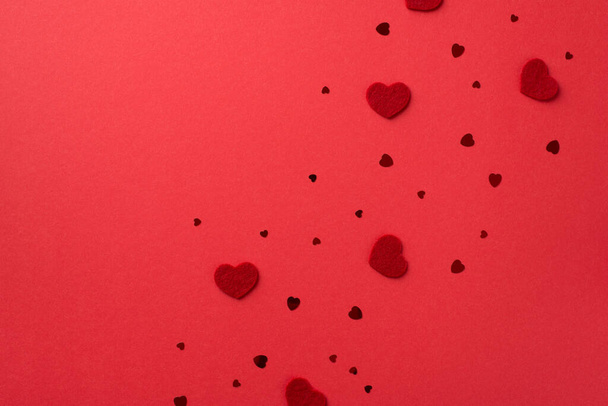 Top view photo of valentine's day decorations decorative hearts and heart shaped confetti on isolated red background with blank space - Фото, изображение