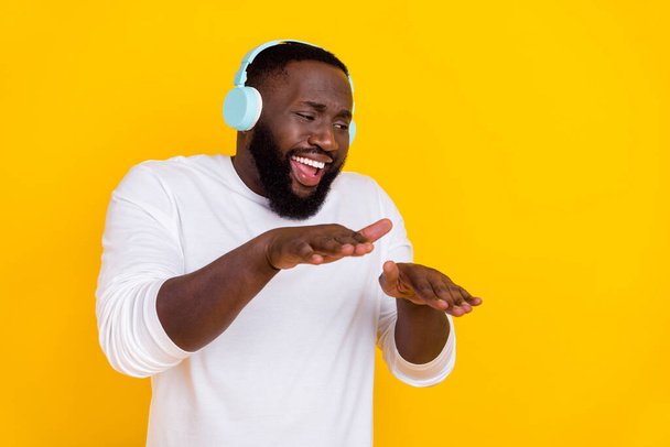 Photo of satisfied cheerful handsome guy listen to favorite single enjoy chill isolated on yellow color background - Fotó, kép