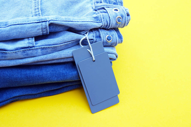 Деталь синіх джинсів, порожні сірі етикетки на жовтому тлі. Покупка і знижка концепції. Чорна п "ятниця. - Фото, зображення