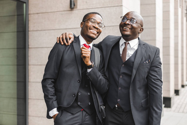 Meeting of two long-time friends of black African American businessman in suits outdoors - 写真・画像