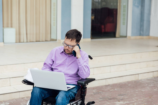ein Mann mit Behinderungen im Rollstuhl arbeitet an einem Laptop im Internet - Foto, Bild