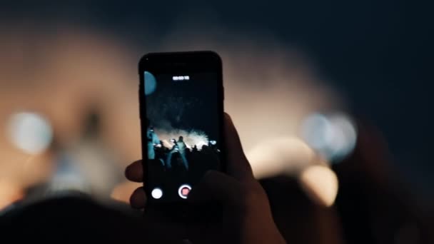 Hands hold smartphones and shoot videos of exploding fireworks in the night sky. - Footage, Video