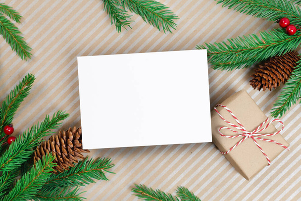 Christmas or New Year greeting card mockup with gift box and fir tree branches with cones - 写真・画像