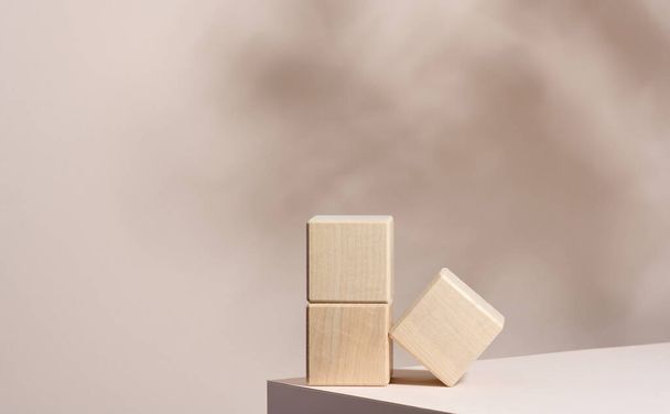 podio de madera para mostrar cosméticos y otros artículos, fondo beige con sombra - Foto, imagen