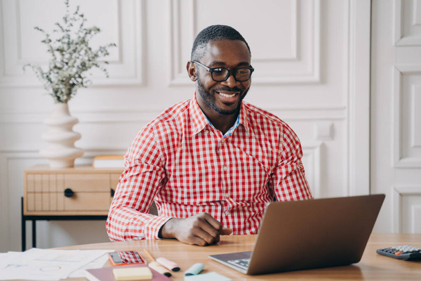 Szczęśliwy Afroamerykanin człowiek biurowy pracownik czat online z partnerem biznesowym przez Internet - Zdjęcie, obraz