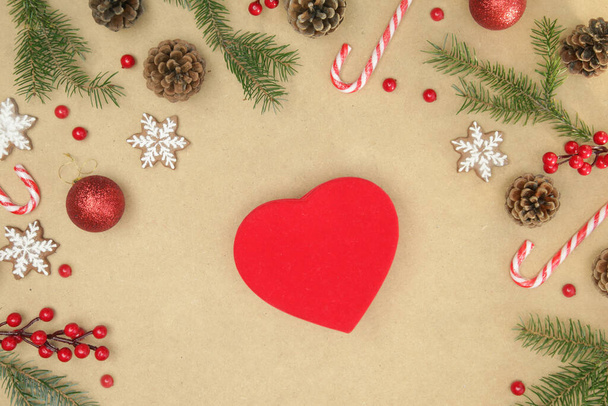 Подарочная коробка в форме сердца на столе с еловыми ветвями, шишками, печеньем и украшениями. Рождество, зимние каникулы, концепция нового года. - Фото, изображение