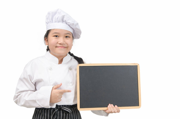 Little asian girl chef in uniform cook holding blackboard for in put text or menu, isolated on white background - Zdjęcie, obraz