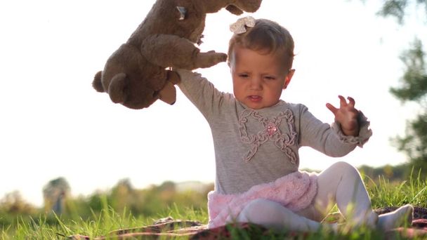 Uma criança irritada joga um brinquedo de ursinho de pelúcia macio no chão. - Foto, Imagem