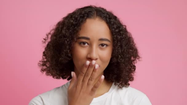 Afroamerikanerin bläst einen Kuss über rosa Studiohintergrund - Filmmaterial, Video