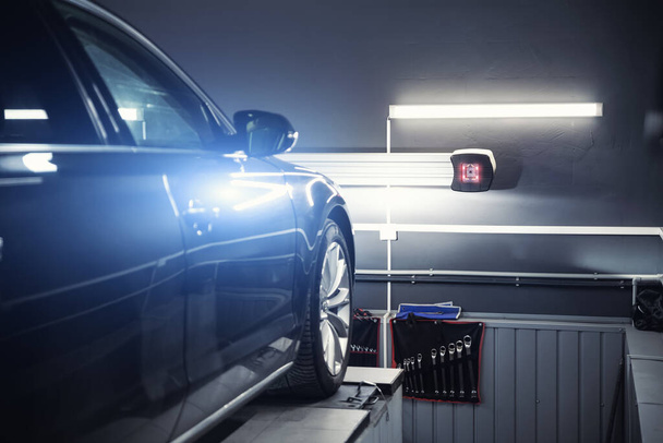 Siyah modern araba servis onarım merkezi lazer sensör ekipmanlarına karşı kontrol ve tekerlek hizalaması için. Otomatik kameralı ayak parmağı kontrolü ve tamirat için garajdaki araç atölyesi - Fotoğraf, Görsel