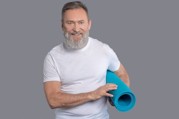 Bearded man holdinga mat for the workout - Photo, Image