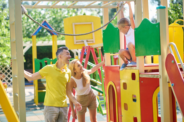 A cute girl spending time with her parents at the playground - Foto, Imagen