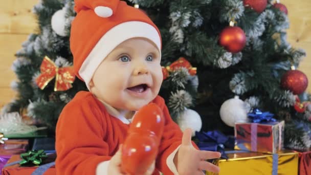 サンタクロースのスーツの子供はクリスマスツリーの近くで遊ぶ. - 映像、動画