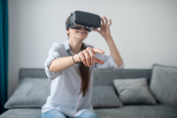 Gamer in the virtual reality headset sitting on the sofa - Фото, изображение