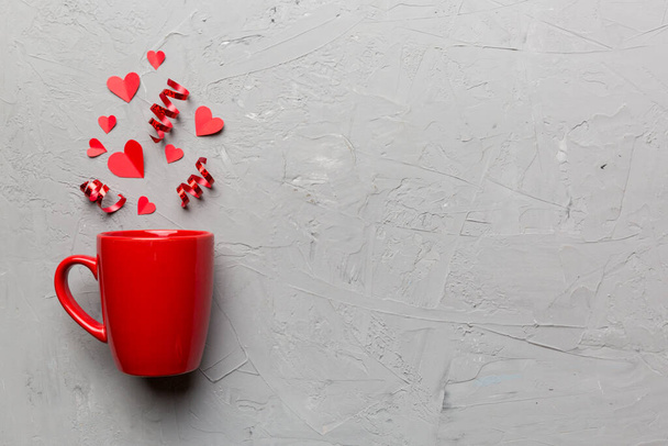 red cup on colored background, splashes of red little hearts, top view with copy space. - Foto, afbeelding