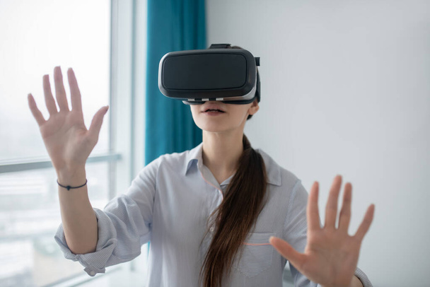 Female gamer in VR glasses standing in a room - Fotó, kép