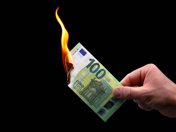 miesten kädessä on 100 euron seteli, joka on eristetty mustalla pohjalla; kuva inflaatiosta - Valokuva, kuva
