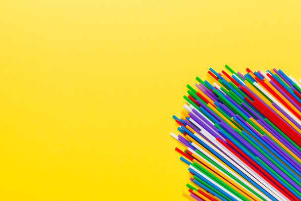 Heap of colorful plastic drinking straws on Colored background, flat lay. Copy Space for text. - Photo, Image