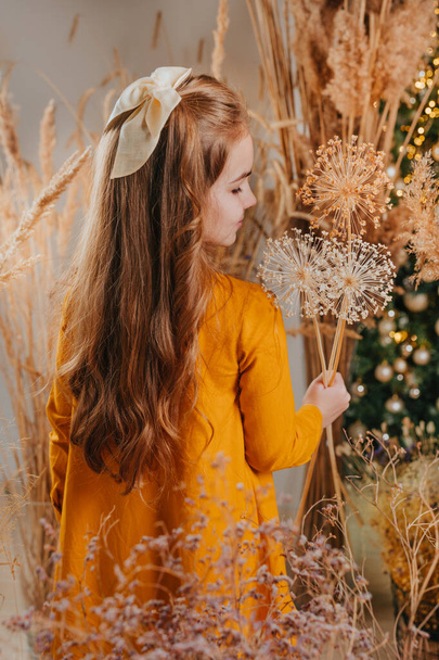Gyönyörű kislány, szárított virágokkal a kezében. Boho stílusú gyerekek ruha. - Fotó, kép